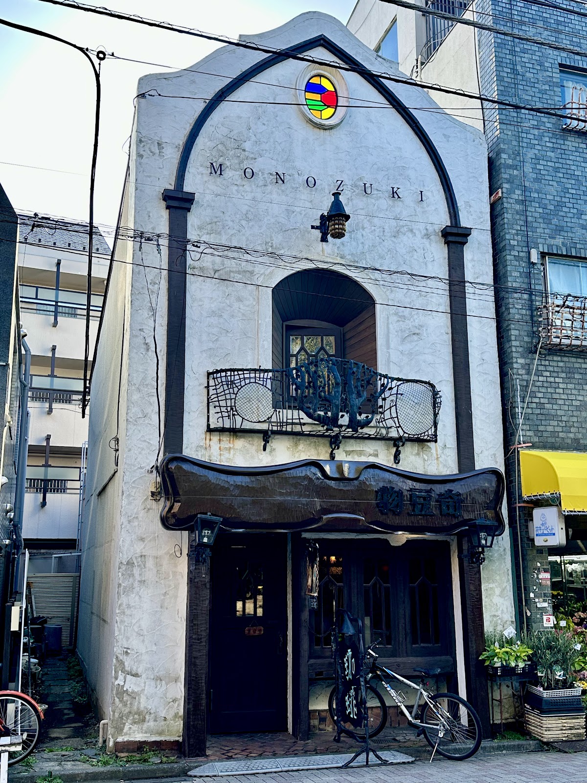 白漆喰の外壁にステンドグラスの丸窓とMONOZUKIの文字、黒いアーチ装飾が施された2階建て外観